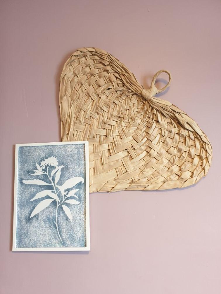 Décoration du cabinet de sophrologie : tressage naturel et cadre végétal sur un mur rose poudré.